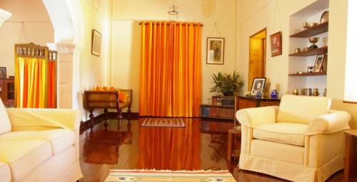 Mirror finish flooring in a hall having two sofas and orange themed settee and curtains 